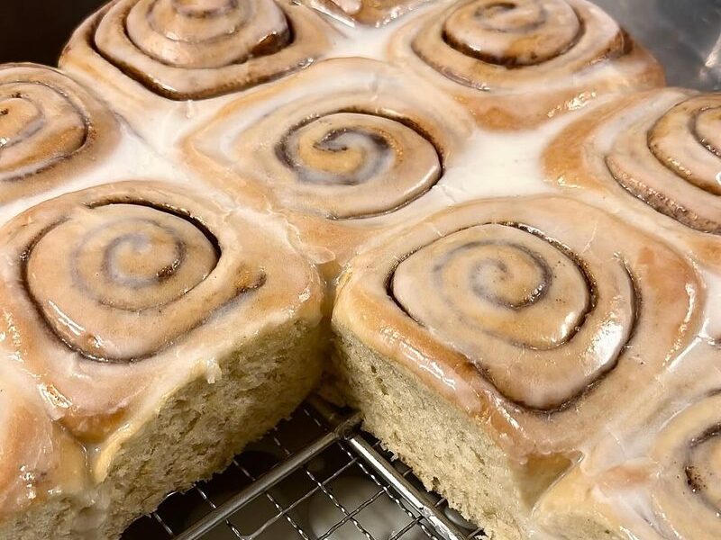 Glazed cinnamon scrolls fresh out of the oven on a cooling rack