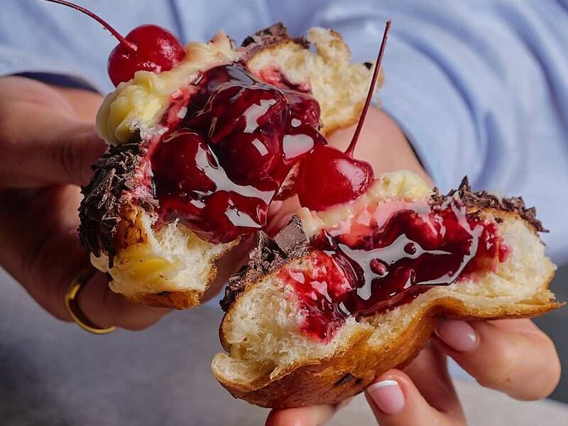 A brioche doughnut pulled apart with cherries and chocolate